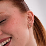 The model smiles with her eyes closed while showing off the 14K Solid Gold Initial Stud Earrings styled on her earlobe.