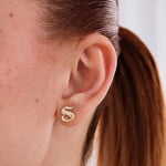 Close-up of a woman's ear wearing a 14K Solid Gold Initial Stud Earring shaped like the letter "S" in a bold, modern font.