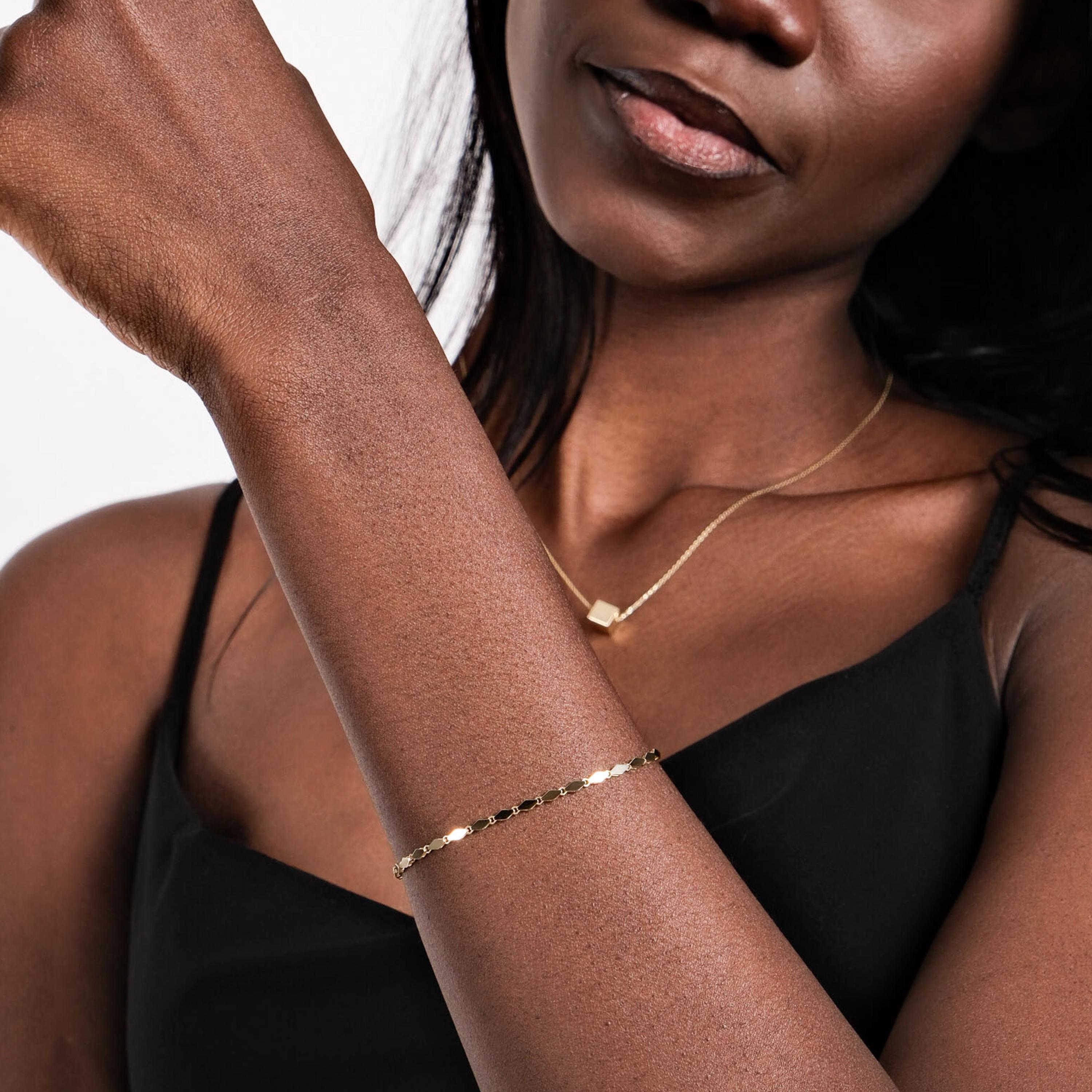 A model wears the dainty 14K gold bracelet, paired with a minimalist gold necklace.