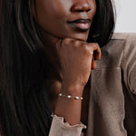 A stylish woman in a beige top gently resting her hand, emphasizing the timeless beauty of the 14K solid gold freshwater pearl bracelet.