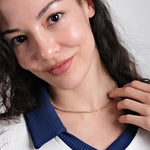 A woman gently touching her 18K Gold Vermeil Paperclip & Tennis Necklace, highlighting its elegance.