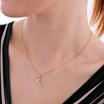 14K solid gold custom letter necklace with butterfly accent, focusing on the engraved "E" pendant on soft fabric.