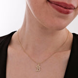 The 14K solid gold cursive initial necklace catches the light, highlighting the elegant "B" letter charm.