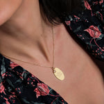 A side view of the engraved gold necklace resting against the wearer’s collarbone, highlighting its delicate chain and sentimental engraving.