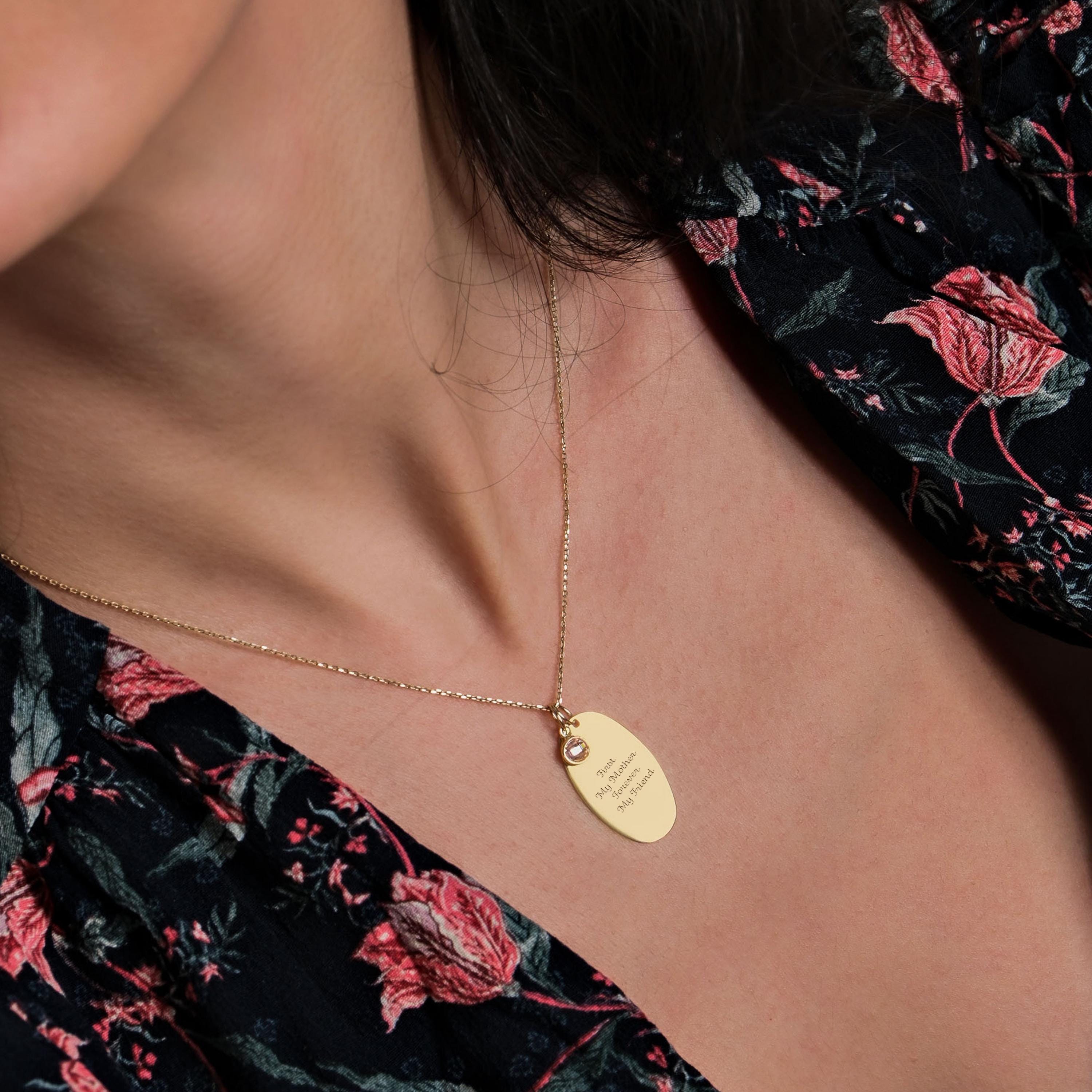 A side view of the engraved gold necklace resting against the wearer’s collarbone, highlighting its delicate chain and sentimental engraving.