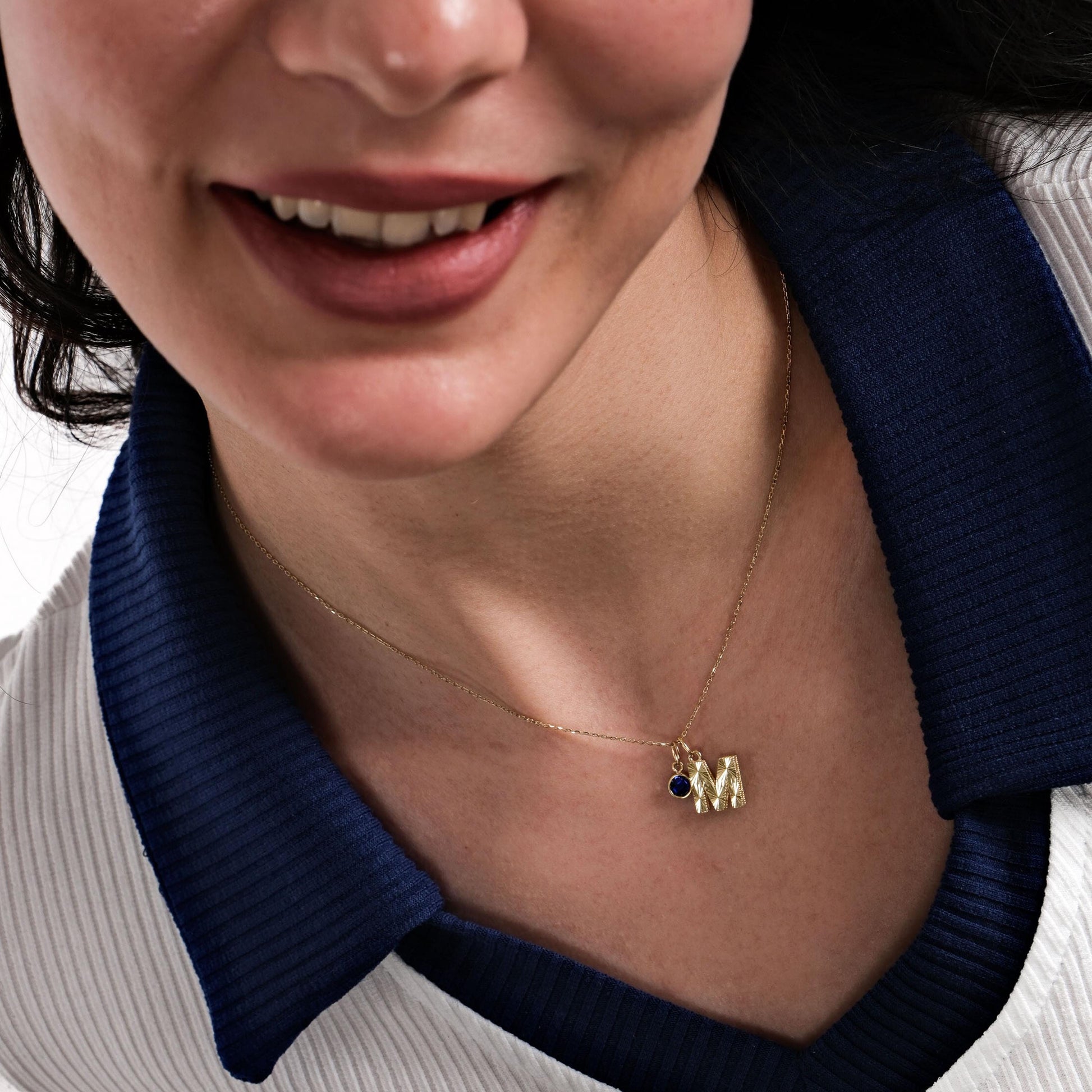 A gold initial necklace with a sapphire birthstone gracefully resting on a woman&#39;s collarbone, highlighting the timeless beauty of the 14K Solid Gold Initial Necklace with Birthstone.