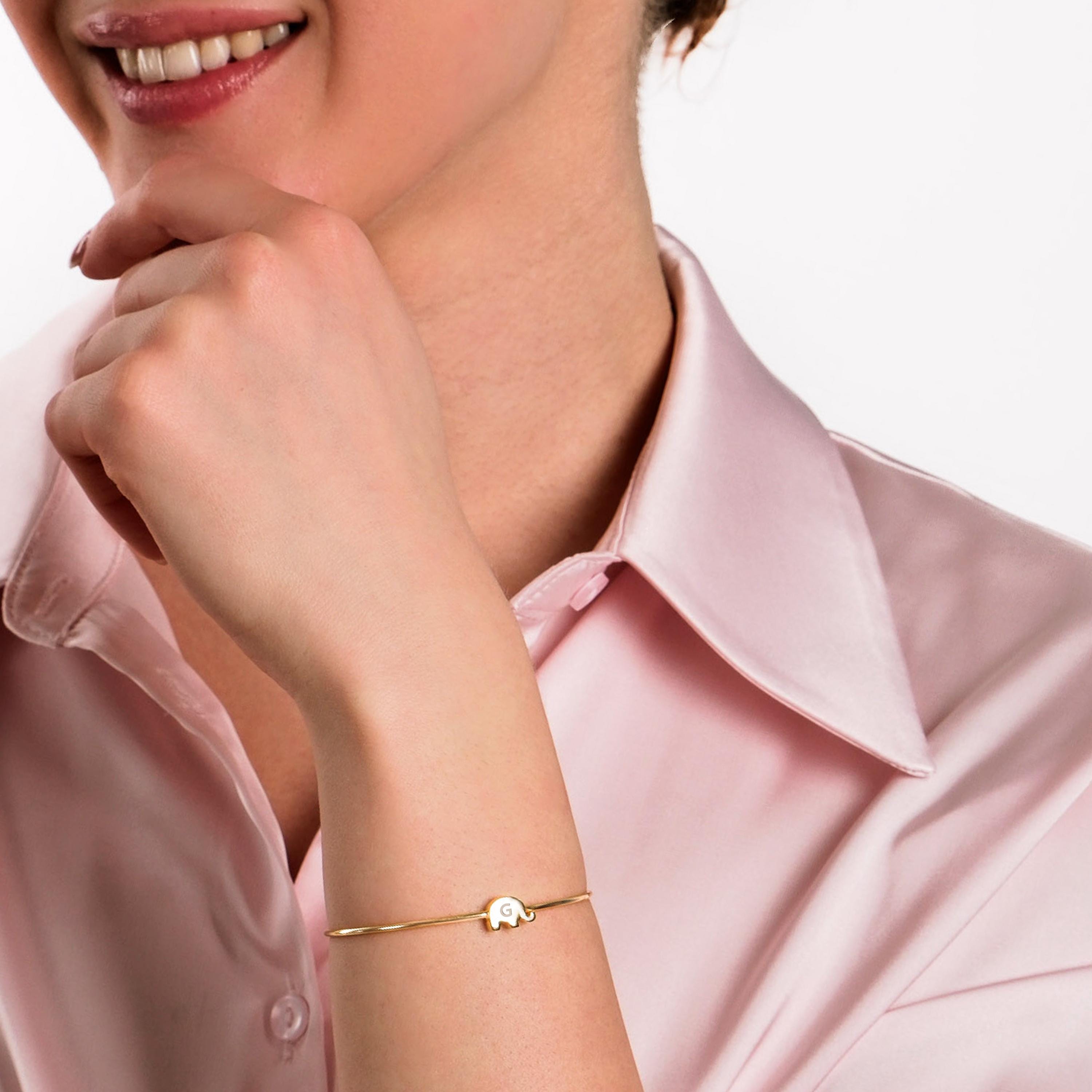 A minimalist gold bangle visible as the model rests her chin on her hand.