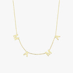 Detailed close-up of the "MAMA" letter charms on a 14K solid gold necklace, photographed against fair skin.