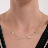 Front view of a 14K solid gold mama necklace resting on a woman’s collarbone, each letter spaced evenly along a delicate chain.