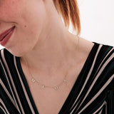 Woman smiling while wearing a 14K solid gold mama necklace, paired with a striped top and natural makeup.