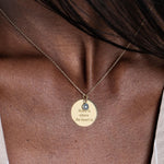 14K Solid Gold personalized disc necklace with an engraved message, resting delicately on the collarbone.