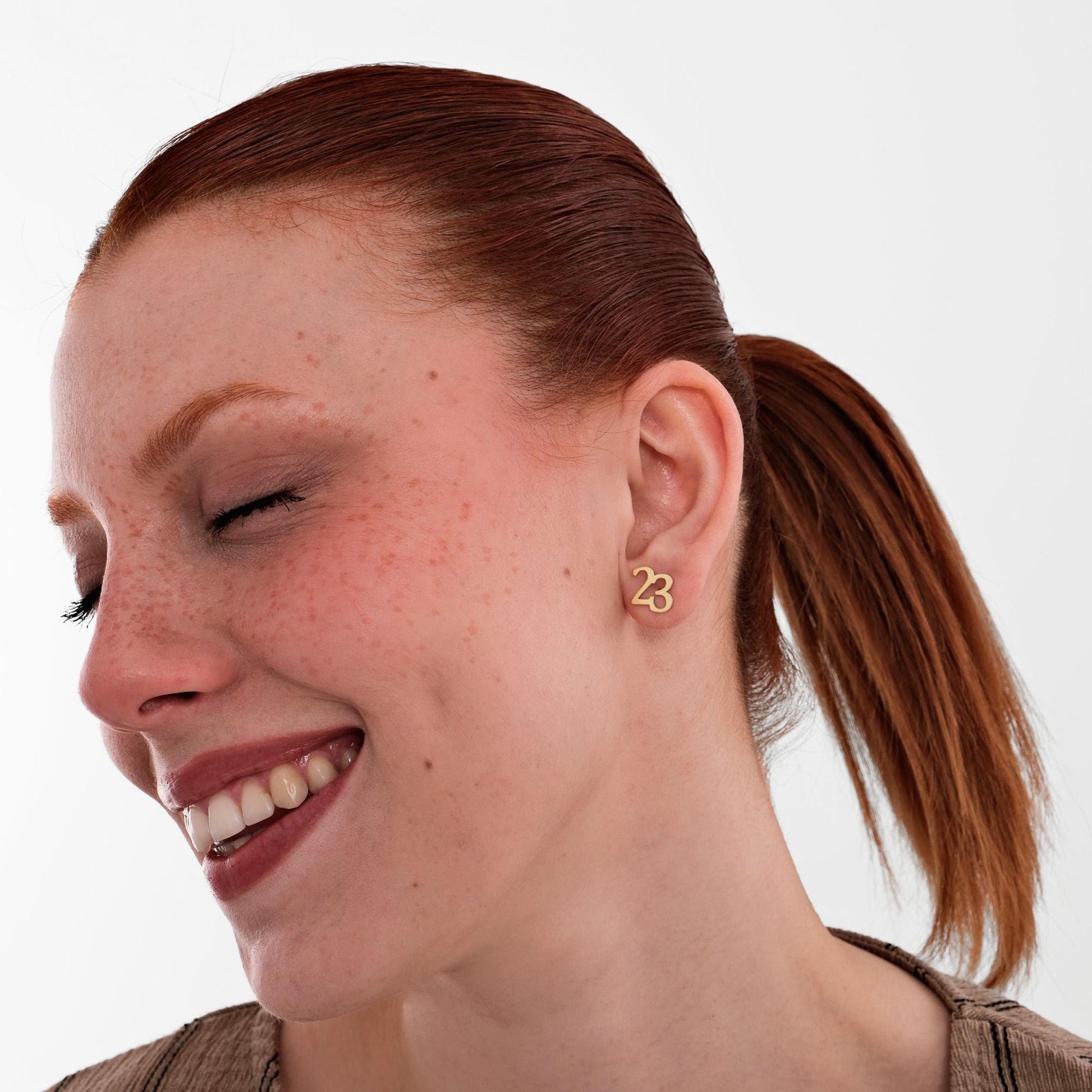 Playful and charming, the 14K solid gold number stud earring shaped as 23 complements a cheerful expression.