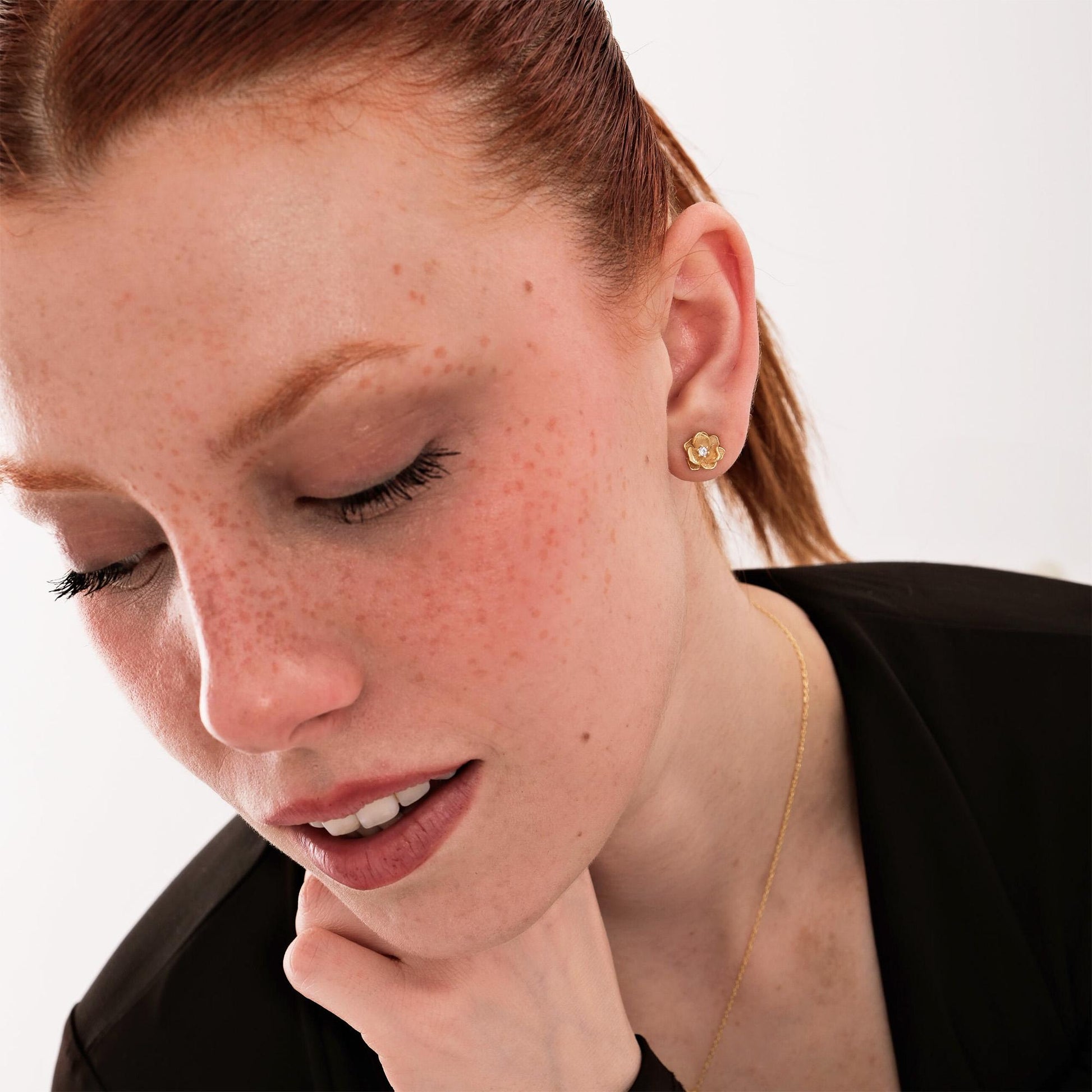 Side view of 18K gold vermeil birthflower earrings worn by a model, highlighting the way they catch the light.