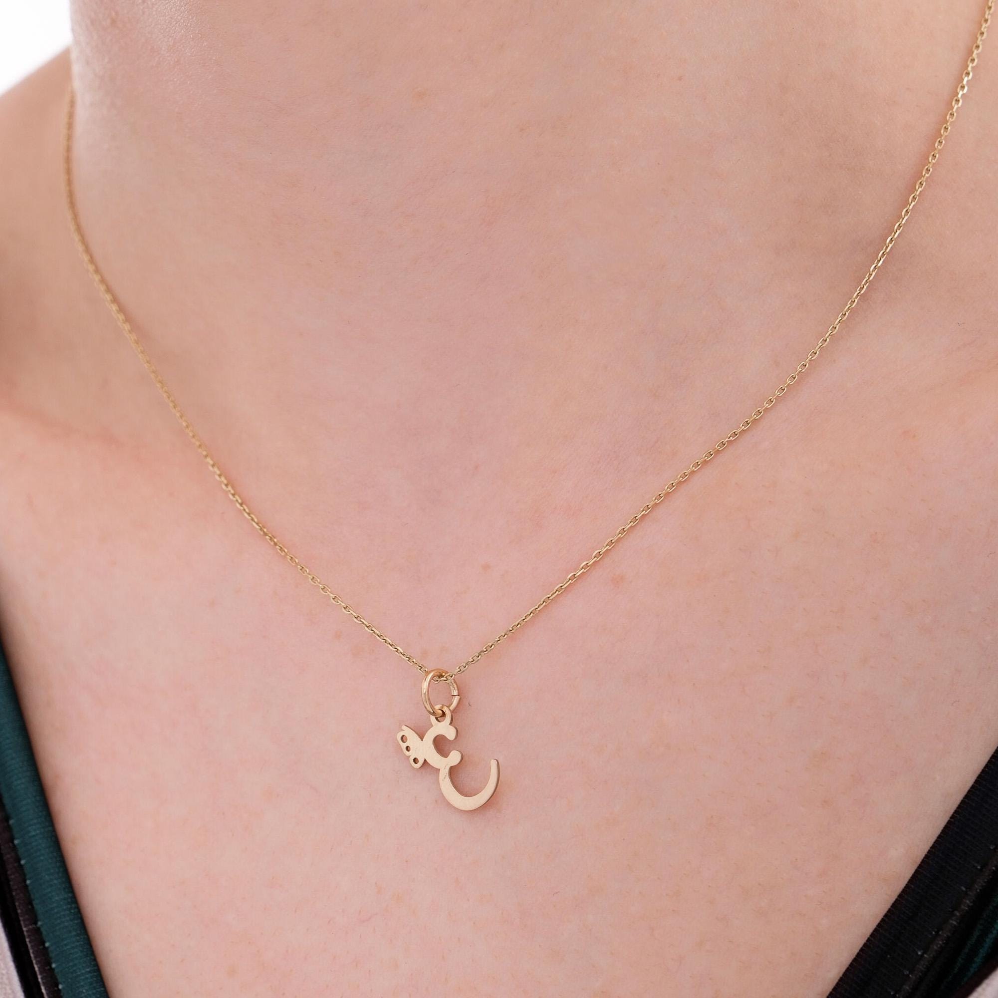 Layered look of 14K solid gold custom letter necklaces with butterfly charms, each showcasing the letter "E" on fine gold chains.