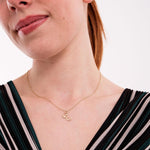 Close-up of a 14K solid gold custom letter necklace with butterfly detail, worn casually, highlighting the delicate "E" initial pendant.