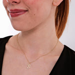 A flat-lay of the 14K solid gold cursive initial "B" necklace shows its delicate chain and heart detail.