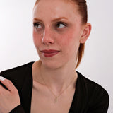 A model wears the 14K solid gold cursive initial necklace with the "B" charm in a casual outfit setting.