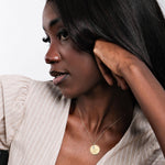 Close-up top view of a 14K solid gold disc necklace engraved with a custom message in elegant script.