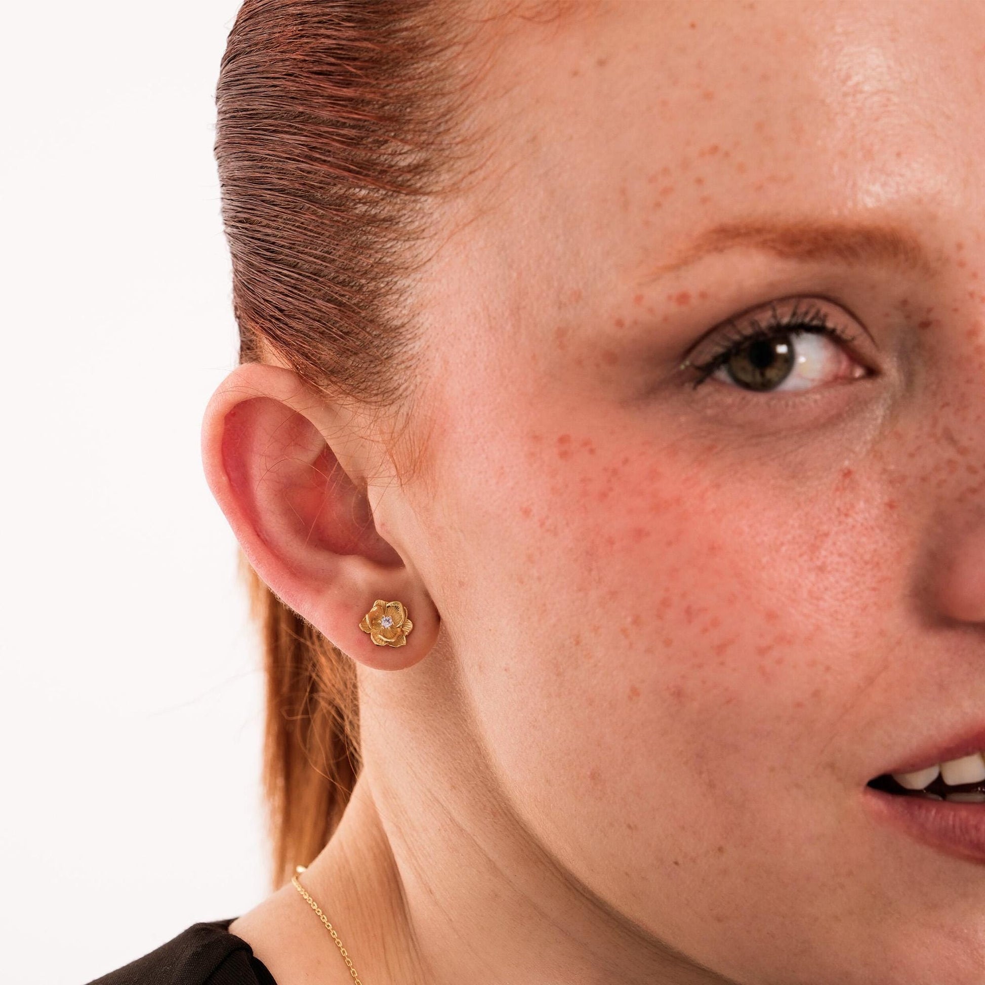 A pair of 18K gold vermeil birthflower earrings displayed in a jewelry box, emphasizing their elegant gold shine.