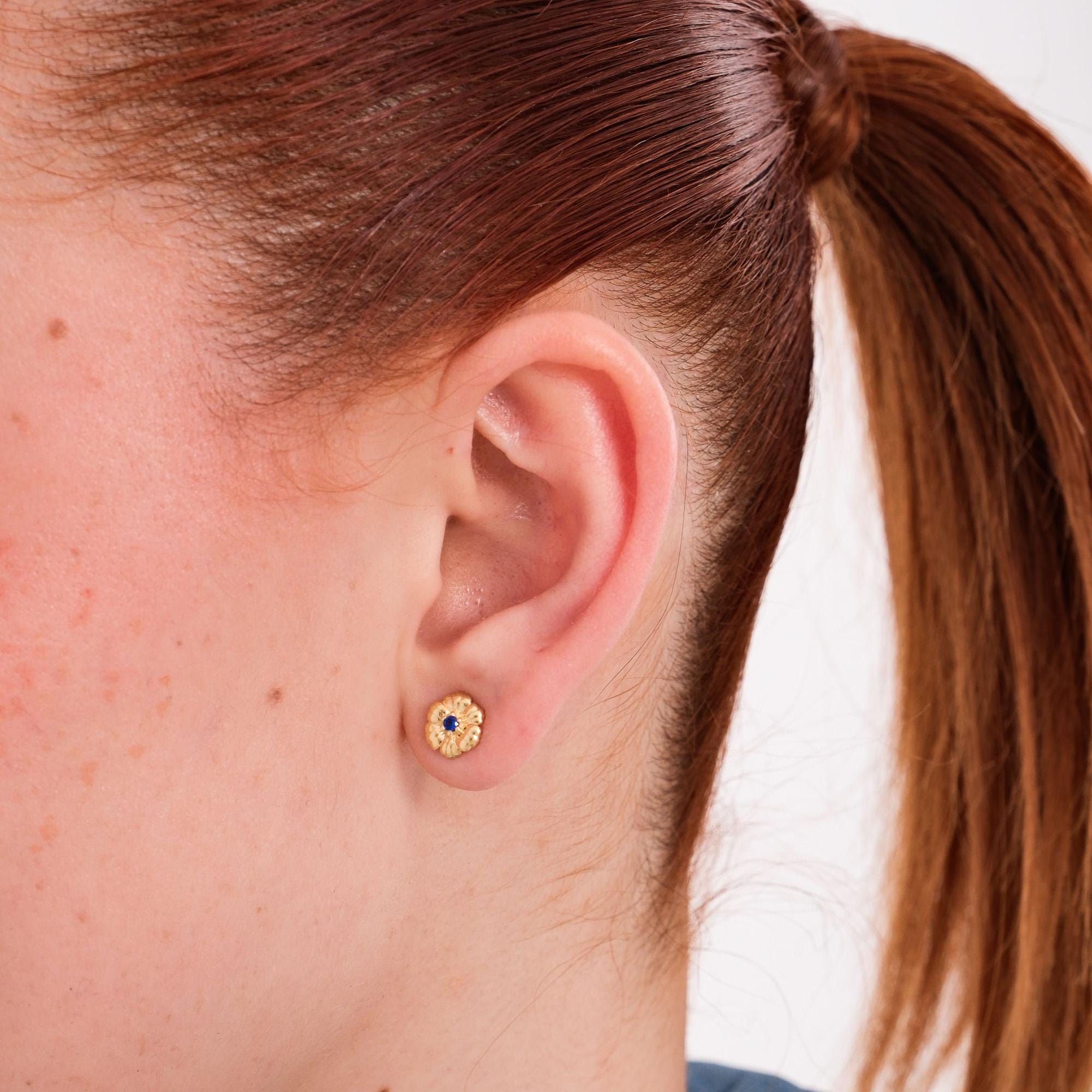 18K gold vermeil birthstone earrings with sapphire accents, worn on the ear to highlight their golden detail.