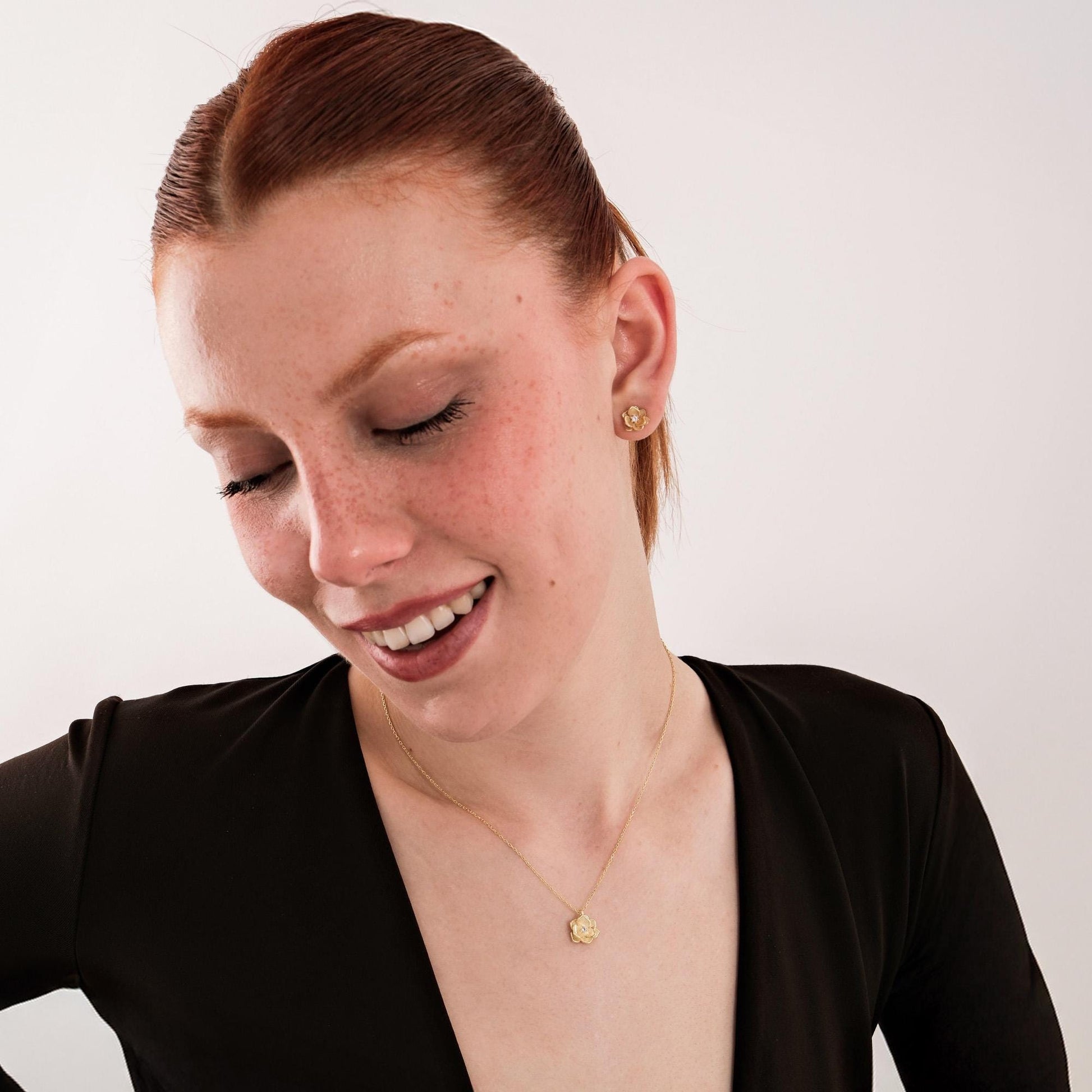 Model wearing 18K gold vermeil birth flower necklace and matching earrings with diamond detail, radiating charm.