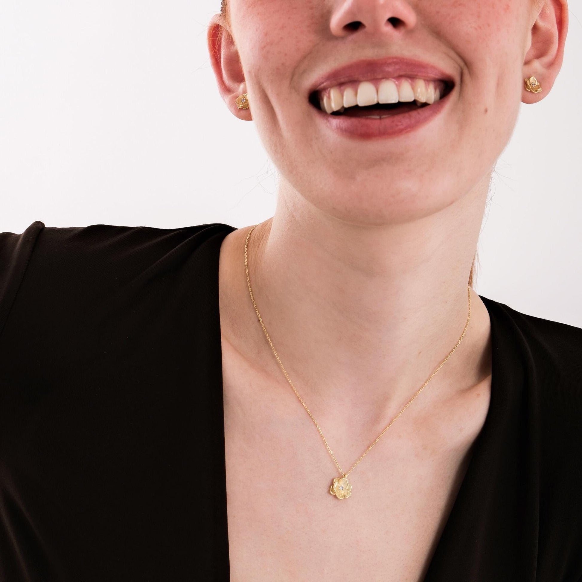 18K gold vermeil birth flower necklace with a sparkling diamond center, laid out in soft curved shape.