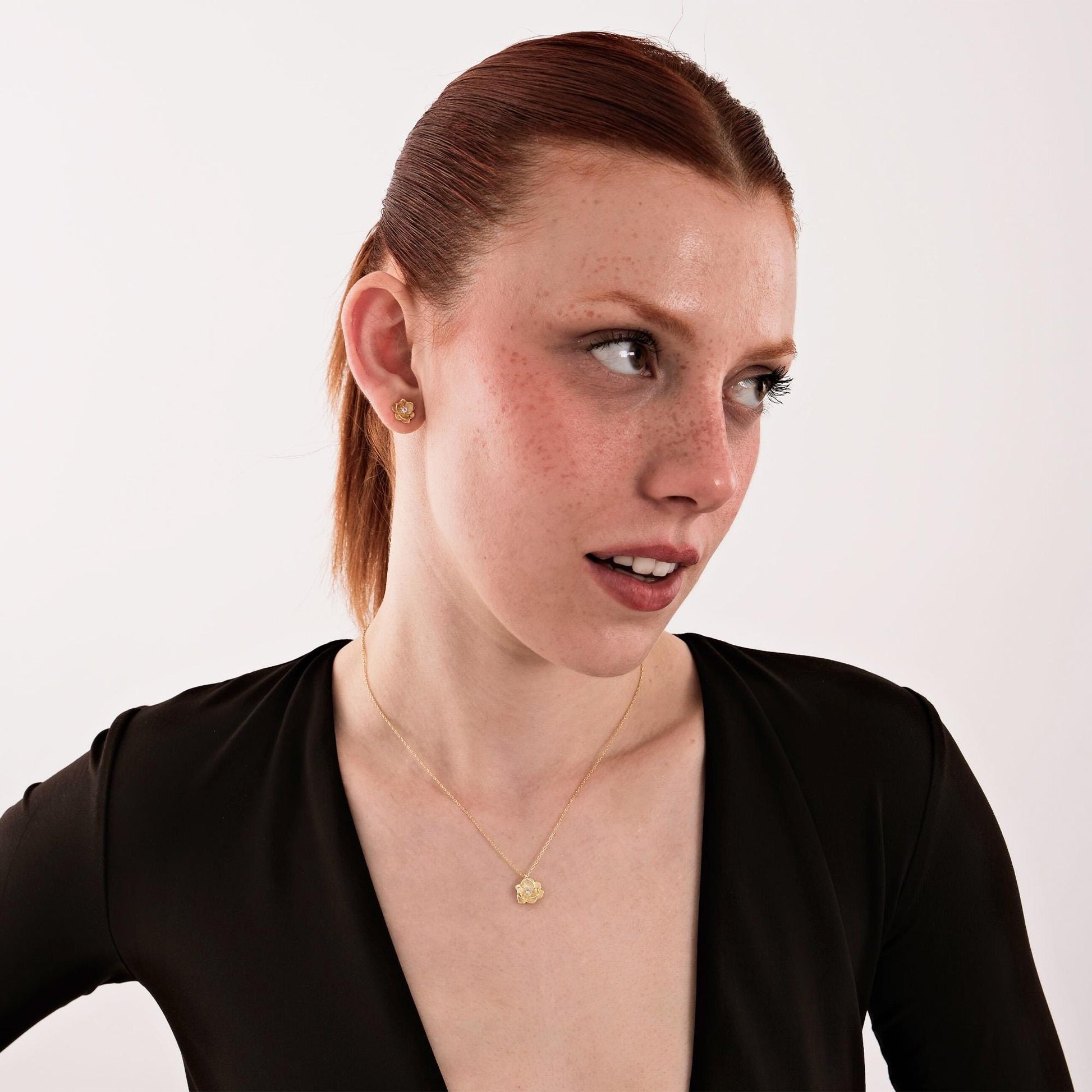 Smiling model displays a 18K gold vermeil birth flower set with diamond accents, worn with joyful expression.