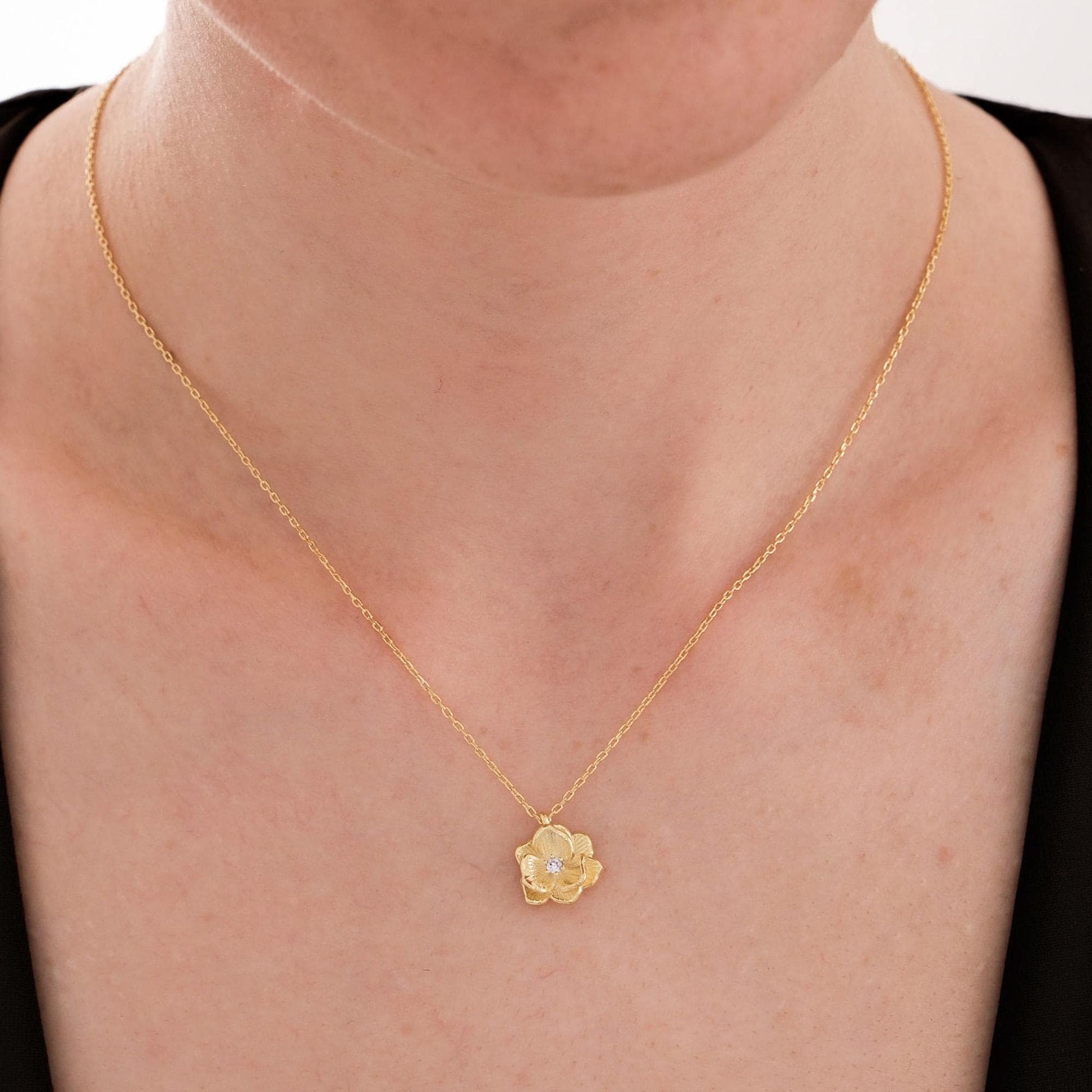 18K gold vermeil birth flower pendant necklace with a diamond center, worn close to the collarbone.