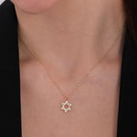 Close-up of a woman’s neck wearing a 14K solid gold Star of David necklace with tiny diamonds on a fine gold chain.