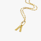 Woman wearing an 18K gold vermeil carabiner charm necklace with paperclip chain and name pendants “NOAH” and “OLIVIA,” styled over a black turtleneck top.