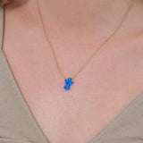 Close-up of a woman’s neck wearing a 14K solid gold lucky symbol necklace with a blue angel pendant and evil eye detail.