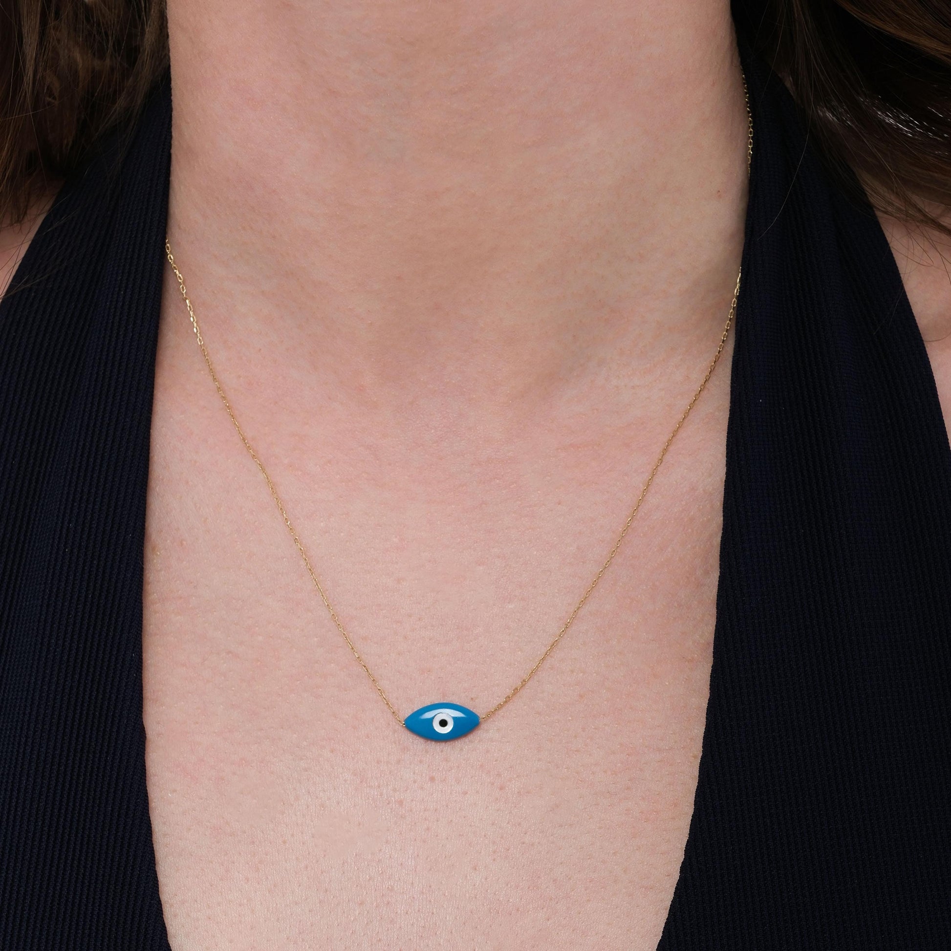 A woman’s neck styled with a 14K solid gold evil eye necklace featuring a sleek blue enamel charm.