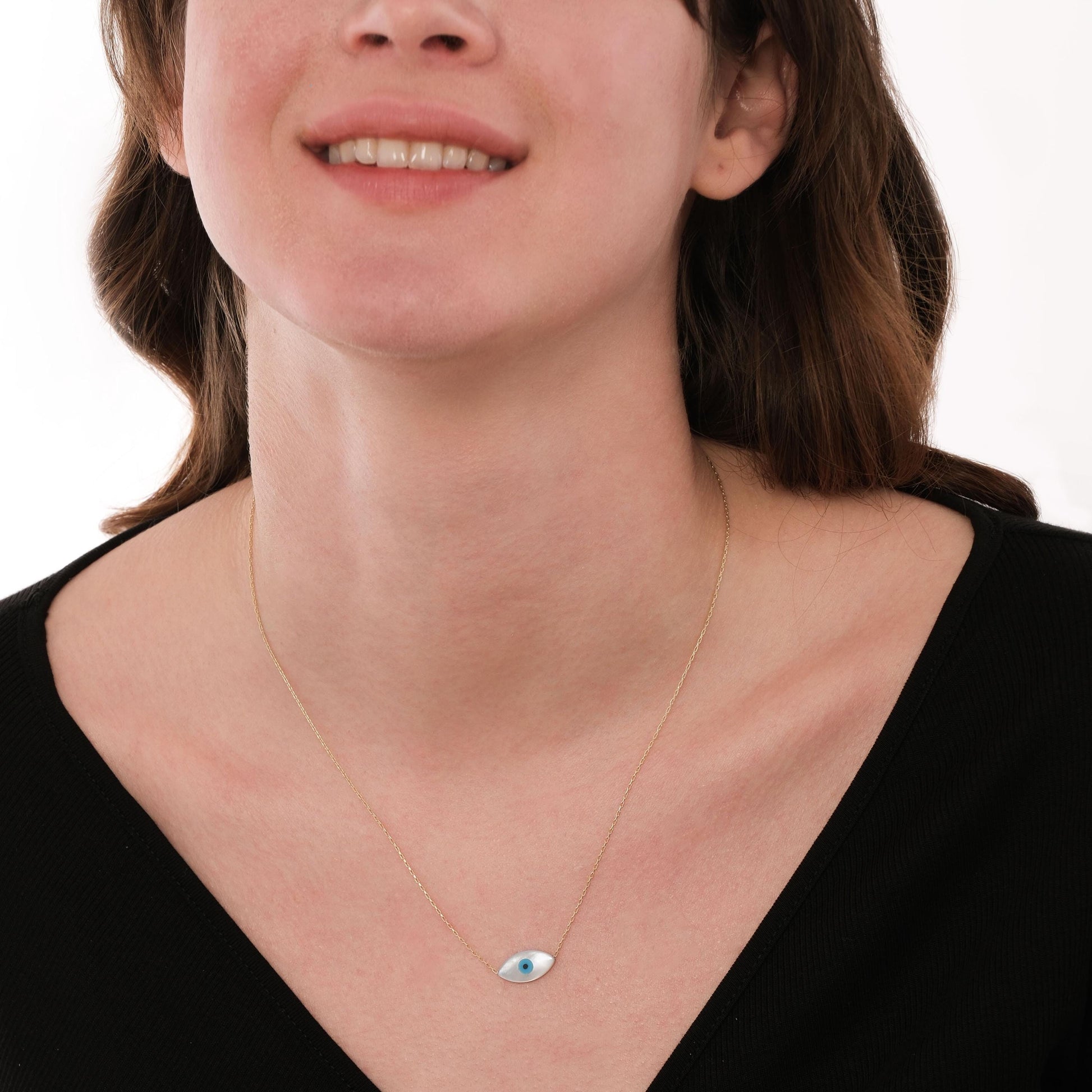Model wearing the 14K solid gold white opal necklace with a soft smile, paired with a deep V-neck black top.