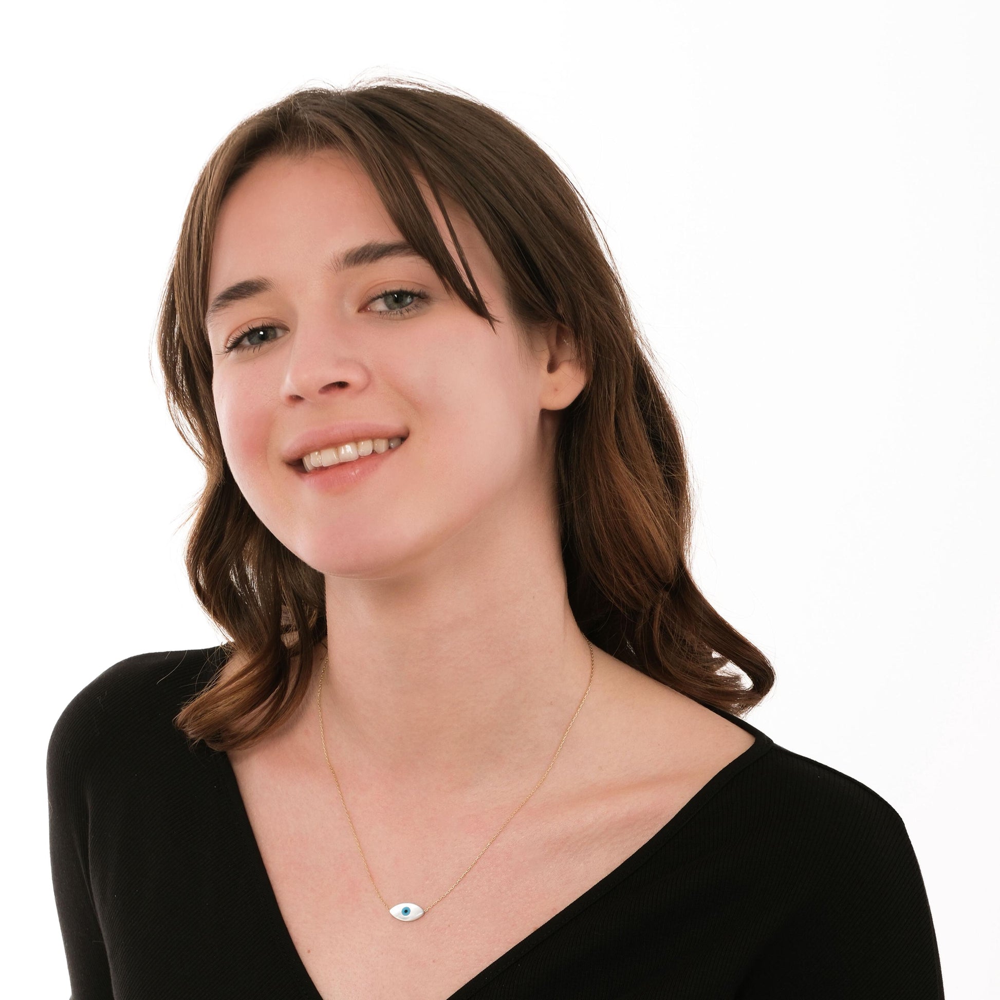 Relaxed portrait of a woman wearing a 14K solid gold white opal necklace, the bright charm drawing gentle focus.