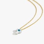 Flat lay of the 14K solid gold cross evil eye necklace with a white cross-shaped pendant and a vivid blue eye detail.