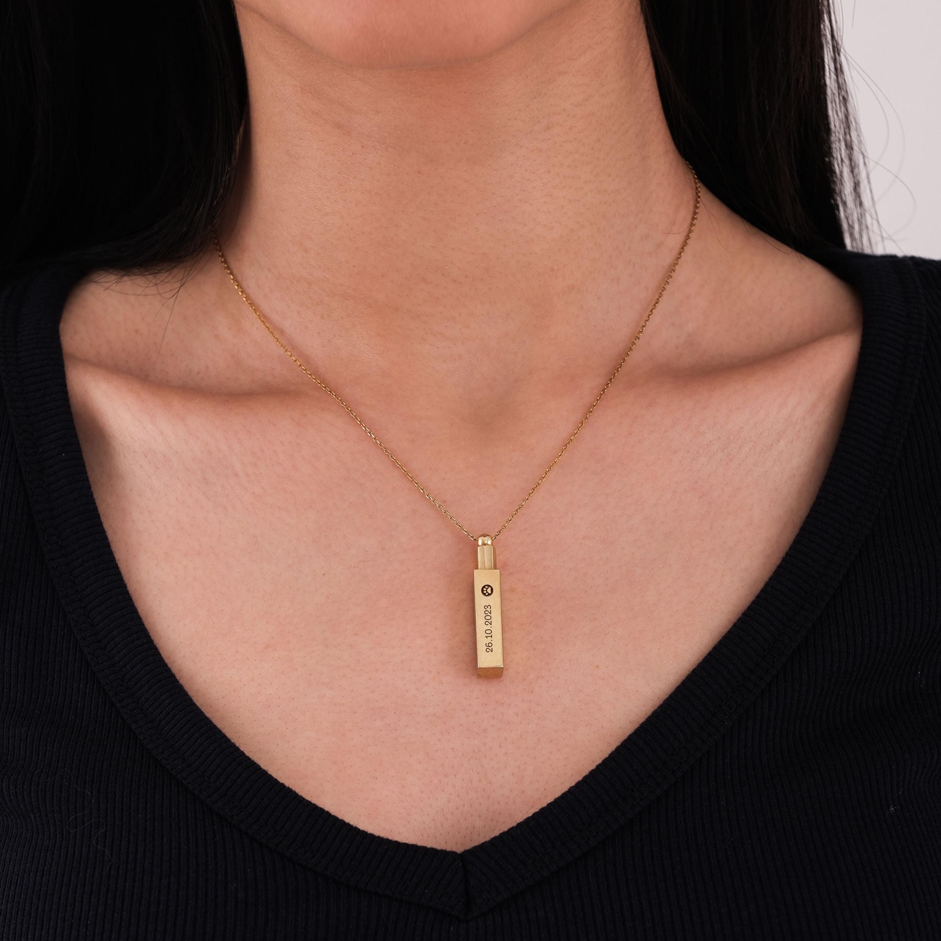 Worn 14K gold plated personalized cremation urn necklace engraved with custom date and icon.