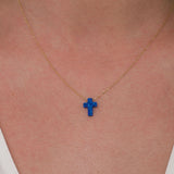 Close-up of a 14K solid gold necklace with a vibrant blue opal cross pendant resting at the center of the neck.