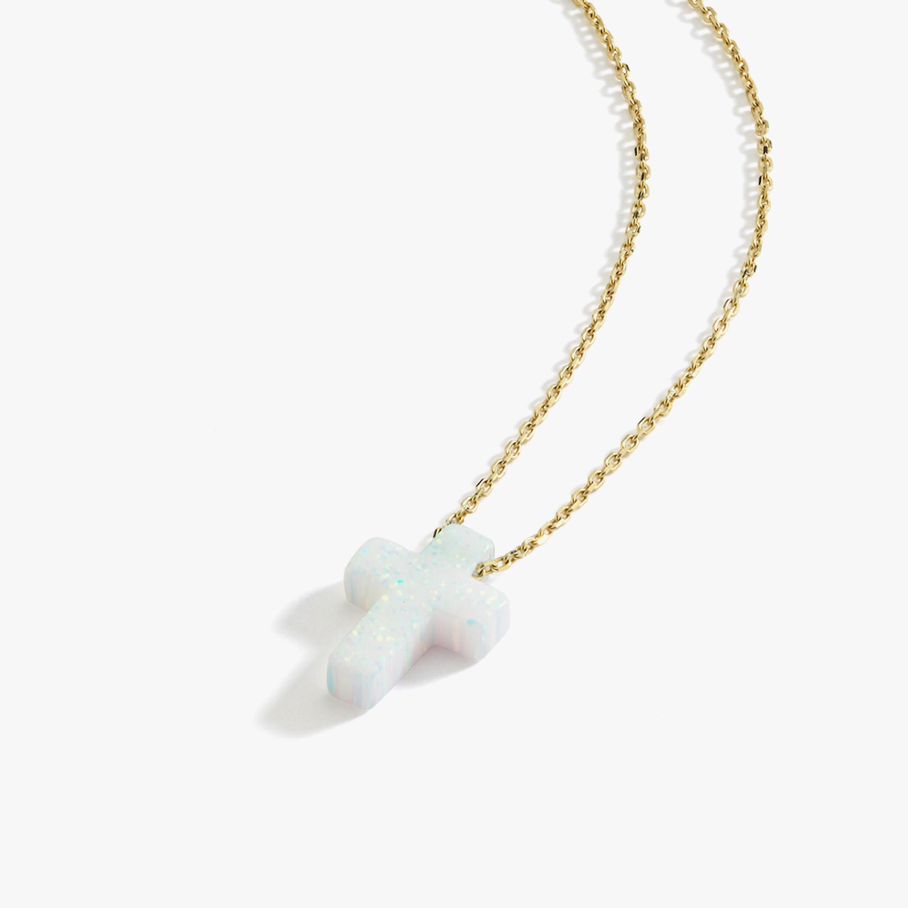 Angled studio shot of a 14K solid gold necklace featuring a white opal cross pendant on a white background.