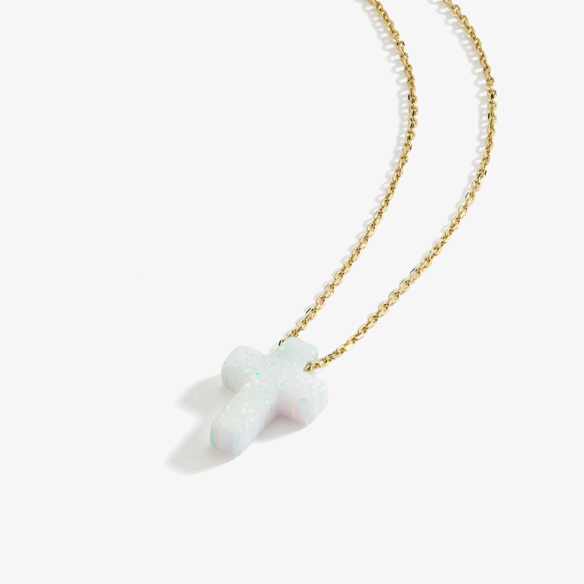 Angled studio shot of a 14K solid gold necklace featuring a white opal cross pendant on a white background.