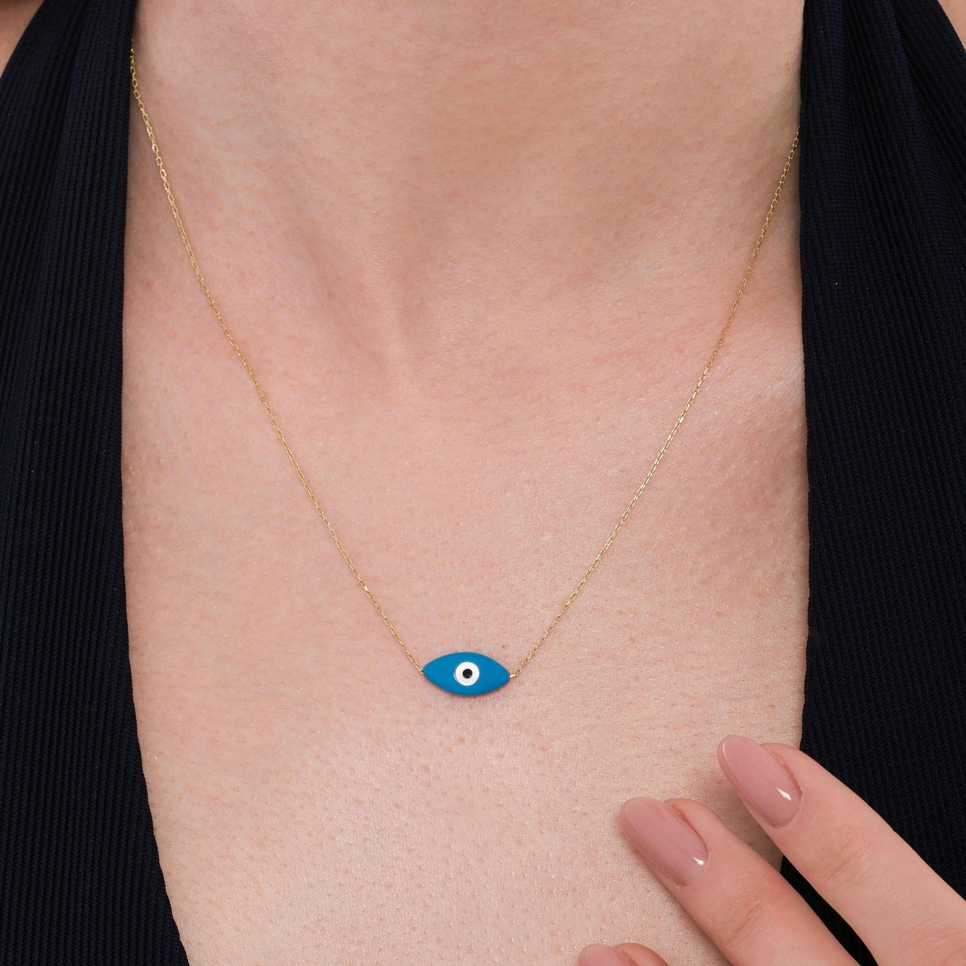 Close-up of a woman wearing a 14K solid gold evil eye necklace with a deep blue eye-shaped charm on a fine gold chain.