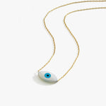 Flat lay of the 14K solid gold white opal necklace showing its smooth oval evil eye pendant with a sky-blue center.