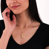 Smiling woman wearing 14K gold plated personalized cremation urn necklace over her chest.
