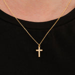 Clear gemstone cross necklace in 18K gold vermeil worn at the center of the neck on a black shirt.