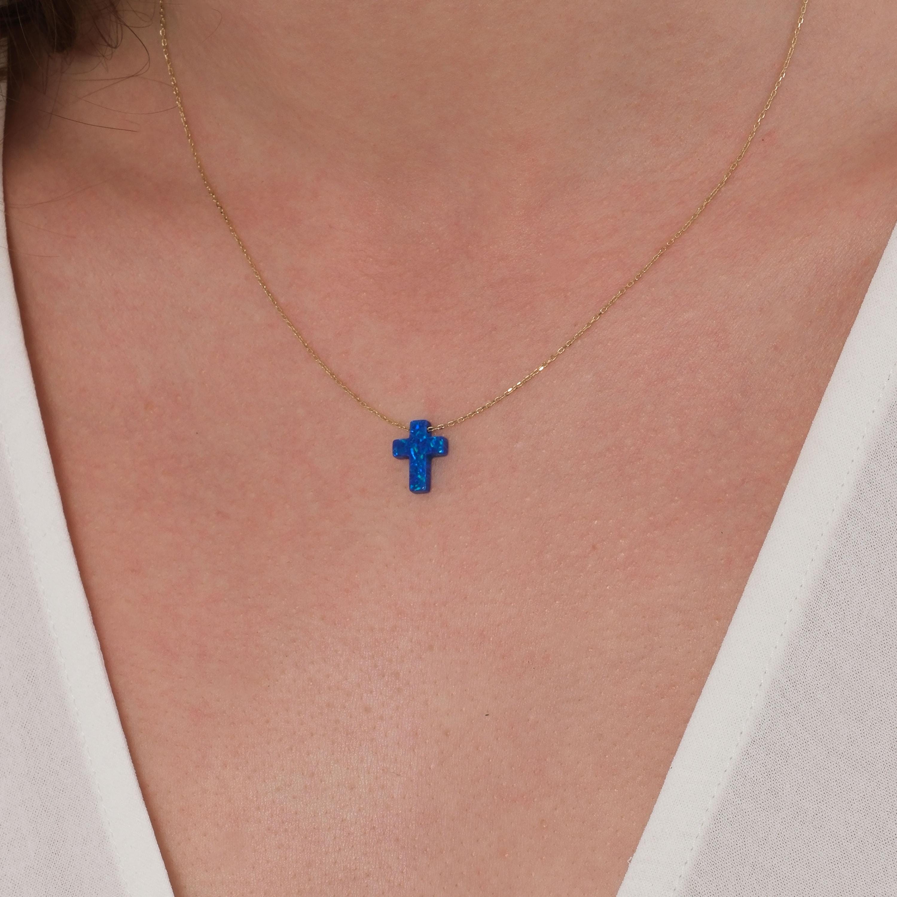 Zoomed view of a blue opal cross pendant necklace on a 14K solid gold chain, styled on the neck.
