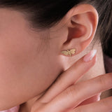 Close-up of a hand gently touching the ear while showcasing a 14K solid gold moth earring.
