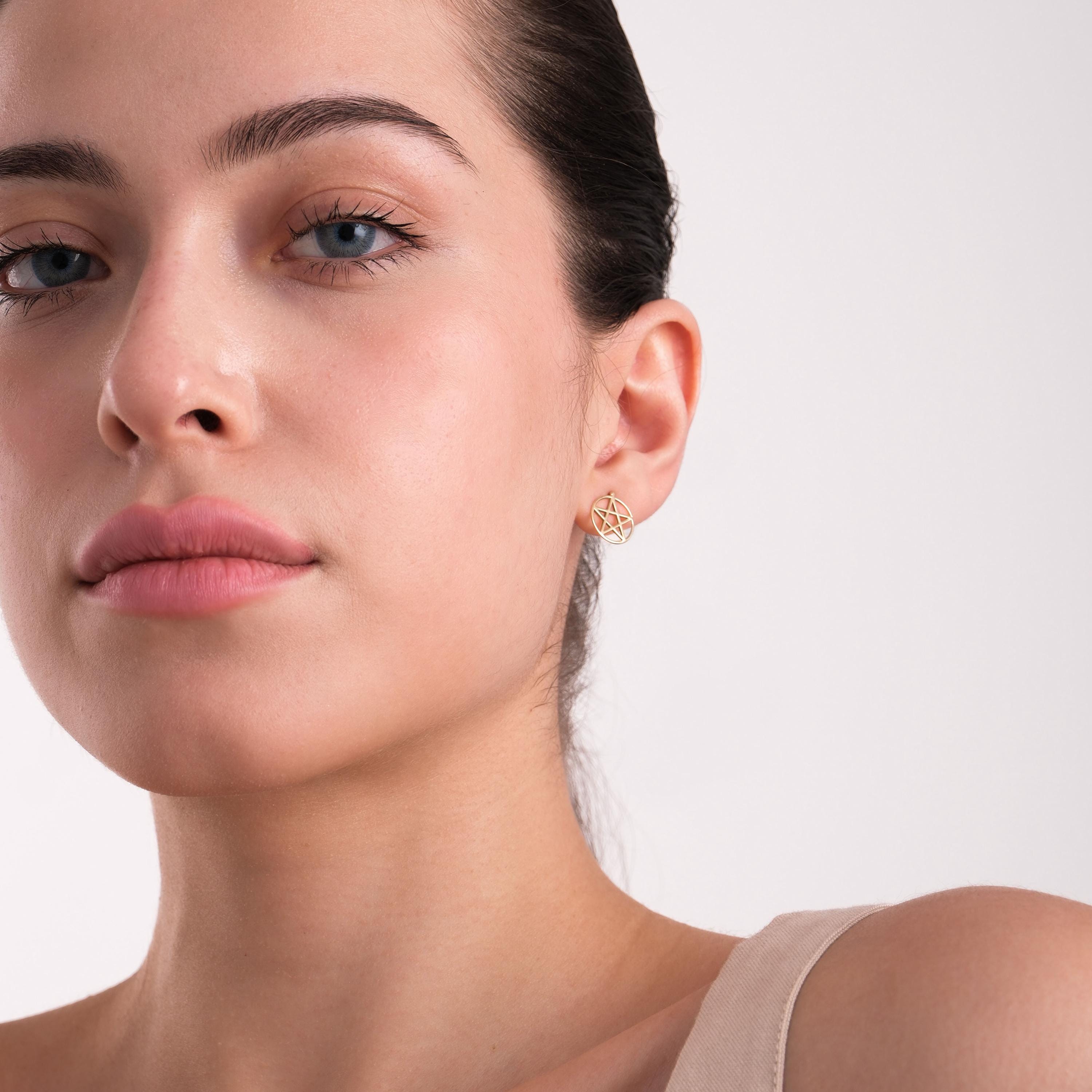 Frontal shot of a woman wearing a 14K solid gold pentagram stud earring with a soft and confident expression.