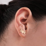 Side view of 14K solid gold triple moon earrings worn on an ear, clearly displaying the central full moon flanked by two crescent moons.