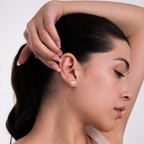 A woman with her hand above her head wears 14K solid gold triple moon earrings, catching light to emphasize their celestial design.