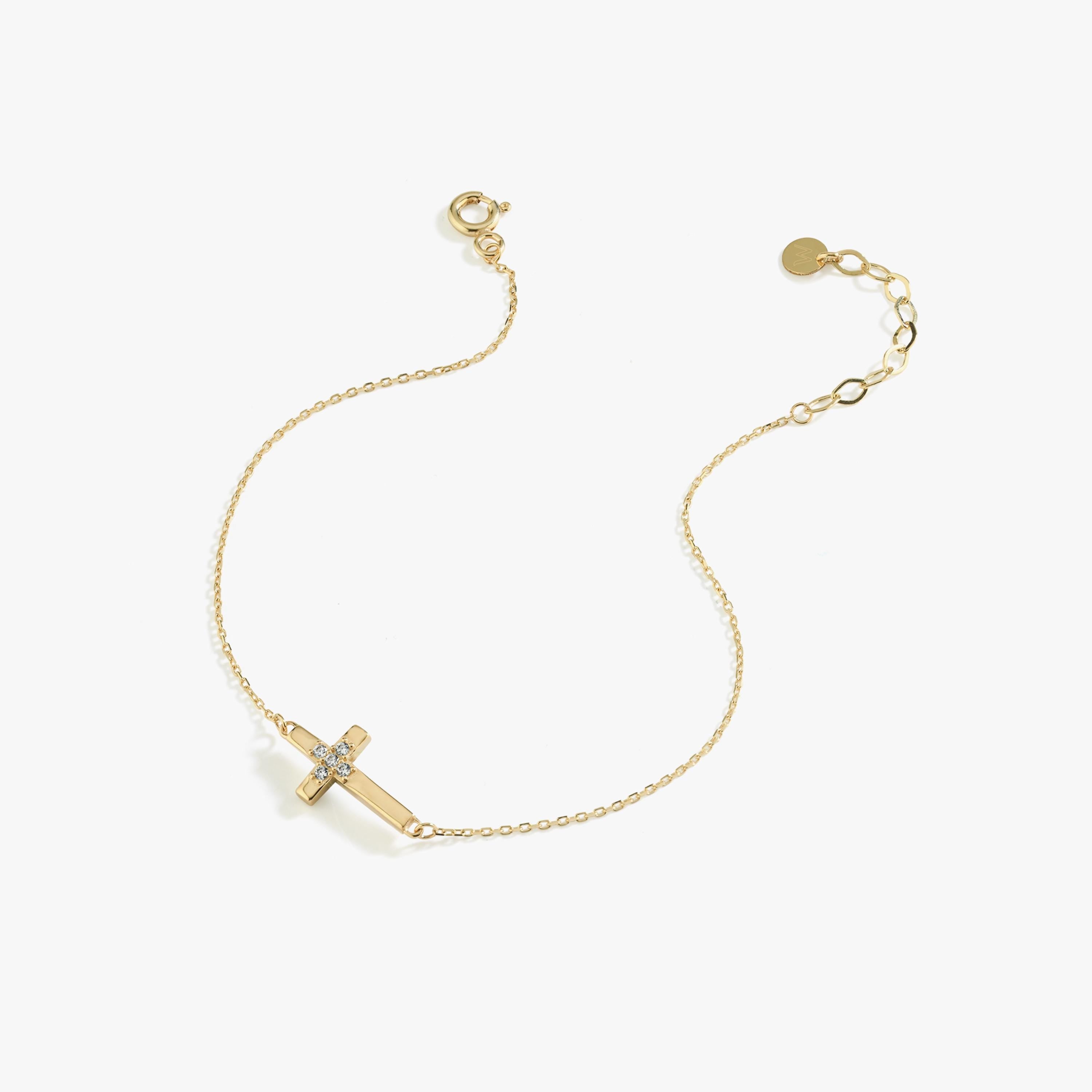 Minimalist 14K solid gold cross bracelet for women with central diamond cluster, displayed diagonally on white background.
