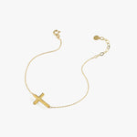 Minimalist 14K solid gold dainty cross bracelet shown on a white background, with a solid bold cross charm and adjustable chain.